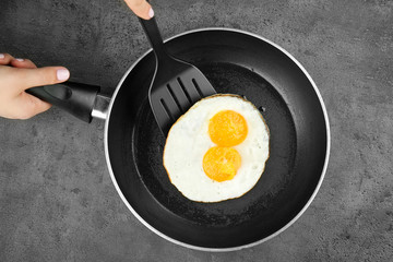 Woman's hands holding pan with over easy fried eggs and spatula