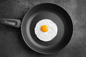 Homemade over easy fried egg in pan on dark background