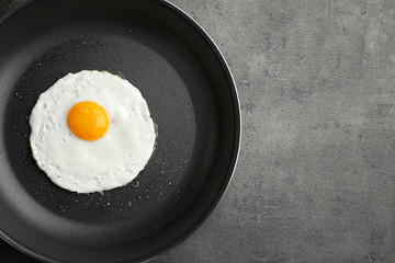 Homemade over easy fried egg in pan on dark background