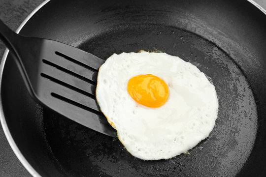 Homemade over easy egg with spatula in frying pan