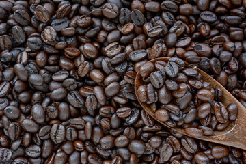 Spoonful of coffee beans on coffee bean heap