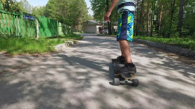 Young boy riding skateboard in summer day. Kid learning to ride longboard in countryside. Active outdoor sport for school kids. Children skateboarding. 