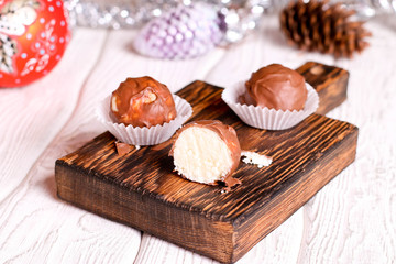 Handmade chocolate coconut candy on wooden table with Christmas and New Year decor.
