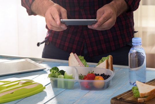 Man photographing lunch box with healthy food