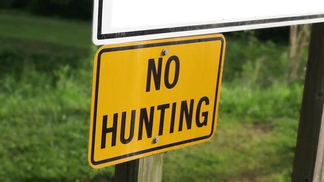 Woman walks past a No Hunting Sign in state park