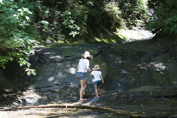 Naklejka na ściany i meble Mother and daughter playing in mountain stream