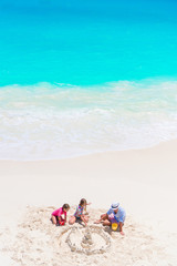 Fototapeta na wymiar Father and little daughters making sand castle at tropical beach. Top view of family playing on the beach