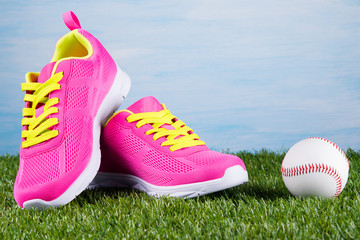 Pink sport shoes on a blue background next to a ball for baseball