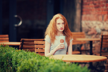 Redhead girl in the cafe with takeaway coffee 