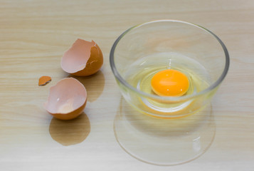 egg in bowl and eggshell on wood background