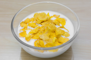 bowl of corn flakes and on wood background