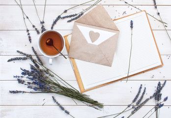 Top view of a cup of tea, lavender, notebook and love letter on a white wooden background. Herbal Tea Letter Note Lavender Love