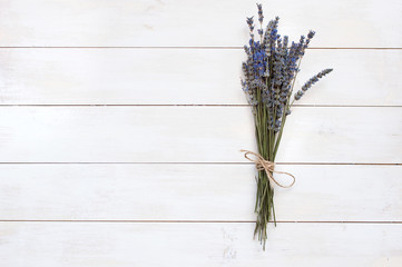 A bouquet of lavender on a white wooden background is a top view.