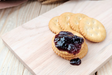 Cracker with jam on woodden background