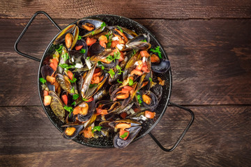 Skillet of marinara mussels on rustic background with copyspace