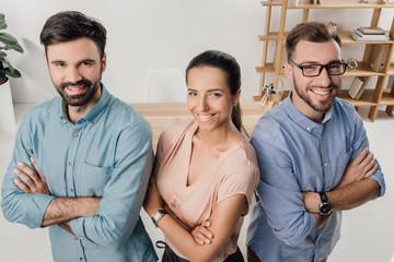 high angle view of smiling business people with arms crossed standing at workplace in office