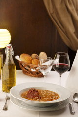 Bean soup arranged in a plate, Wineglass in background, Traditional dish in elegant setting, Selective focus with soft light
