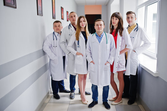 Group of young doctors in white coats posing in the hospital.
