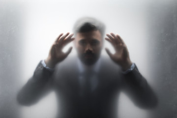 Silhouette of businessman in black suit looking through the glass