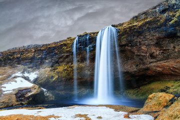 Beautiful view of the Seljalandsfoss waterfall in Iceland with ominous clouds in winter