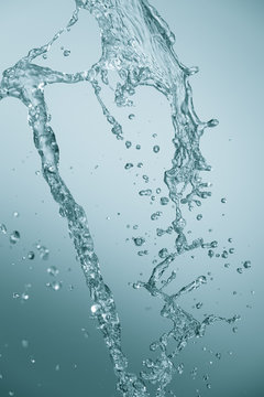 A stream of filtered natural water on a blue background. Splash of mineral drinking water