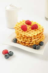 Homemade waffles with berries in plate on grey table