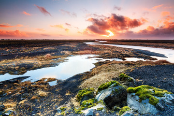 Beautiful black volcanic river landscape of Myrdalssandur in the southern part of Iceland at sunrise in winter. 