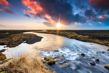 Beautiful black volcanic river landscape of Myrdalssandur in the southern part of Iceland at sunrise in winter. 