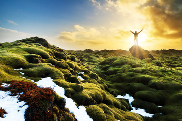 Beautiful tourist posing in the amazing volcanic mossy landscape of Eldhraun at sunrise in Iceland
