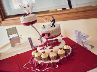 A beautiful sweet creamy Wedding cake with beautiful flowers and decorations, with 3d printed funny bride and groomshot with a shallow depth of field. Love words.