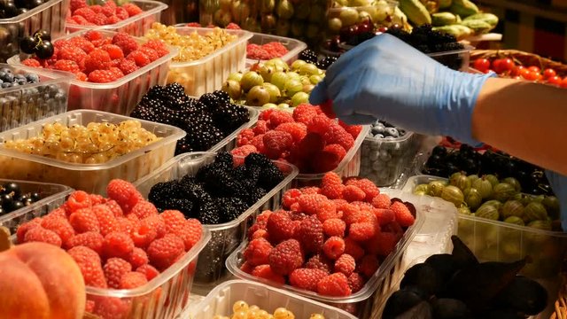 Seller with raspberry near the counter at the market