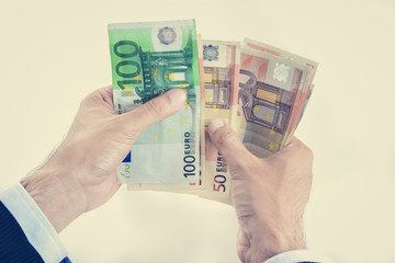 Businessman hands counting money, Euro currency (EUR), in vintage tone