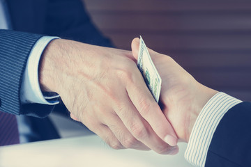 Handshake of businessmen with money - bribery concept