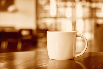 Coffee cup on the table in coffee shop - sepia tone