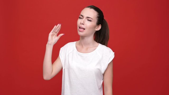 Young beautiful caucasian woman don't want to hear you and covering ears over red background