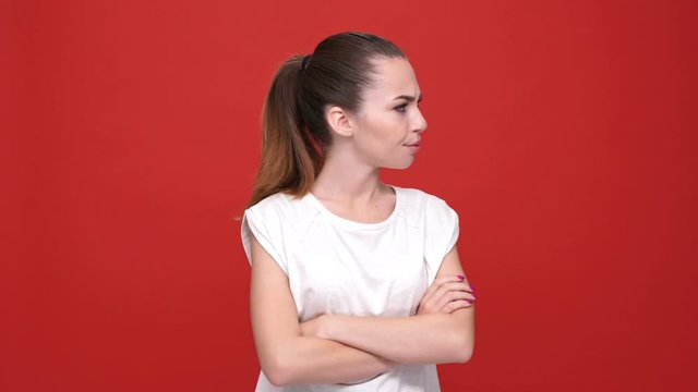 Young angry caucasian woman with arms crossed over red background
