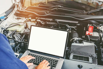 Professional car mechanic working in auto repair service using laptop bon car
