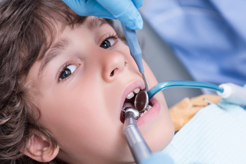 dentist examining teeth of little boy in dental hospital