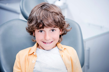 little smiling boy sitting in chair in dentist office