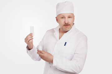 The doctor shows medicines. The doctor in a dressing gown on a white background.