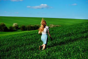 Fototapeta premium Young beautiful woman running on a green field