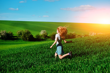 Fototapeta premium Young beautiful woman running on a green field