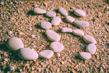 Patterns of stones on the beach. Stones in the form of the sign Om. White pebbles on the bank of...