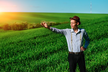 Man on the field shows on elongated hand somewhere far into something