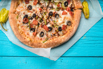Vegetarian pizza with vegetables on blue table.