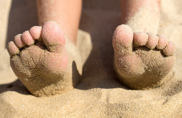 Child feet covered with sand on the beach, detail