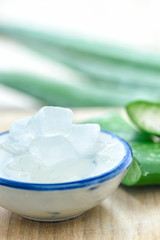 Aloe vera gel on bowl with fresh aloe vera leaves on wooden