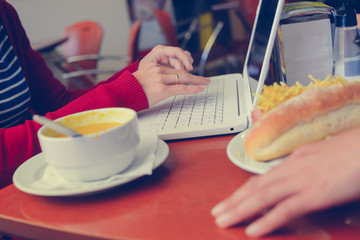 Closeup on busy professional woman typing document on laptop pc computer in cafe. Businessperson using information electronic communication. Eating while browsing mobile wifi internet