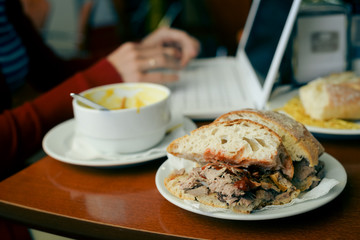 Closeup on busy professional woman typing document on laptop pc computer in cafe. Businessperson using information electronic communication. Eating while browsing mobile wifi internet