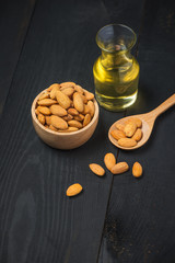 Almond oil in bottle with almonds on  black wooden table
